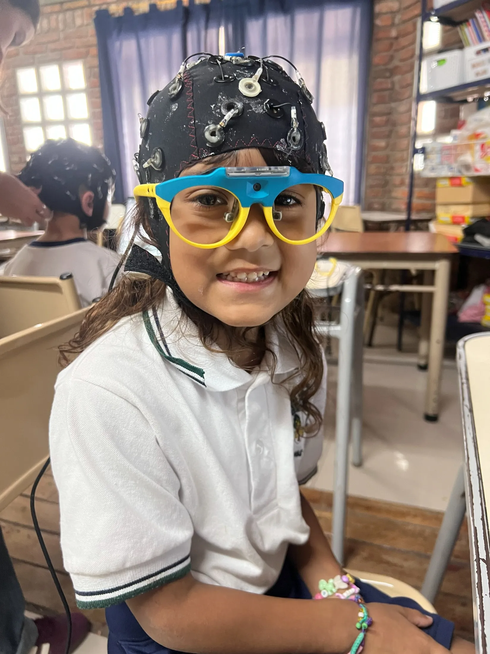 Alumna con un gorro de electroencefalografía durante una investigación en el colegio
